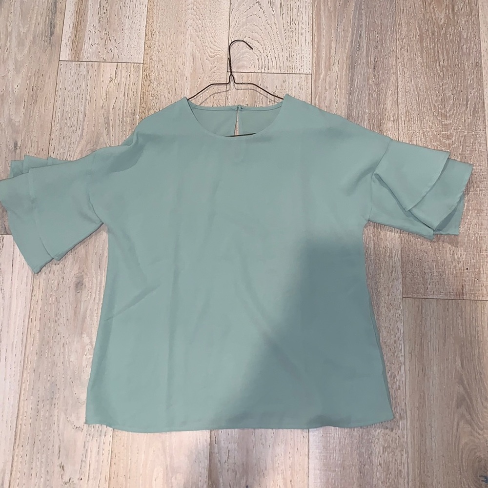 Flowy green top with ruffle sleeves.